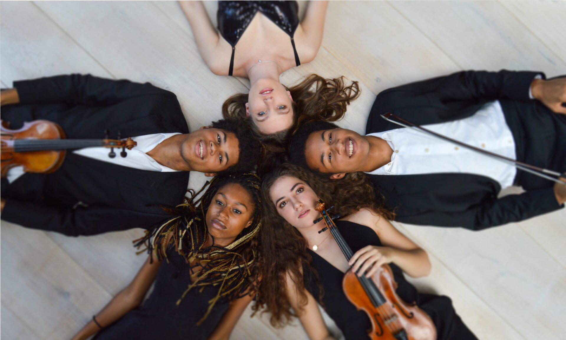 Sheku Kanneh-Mason and friends lie on the ground in a circle holding their instruments