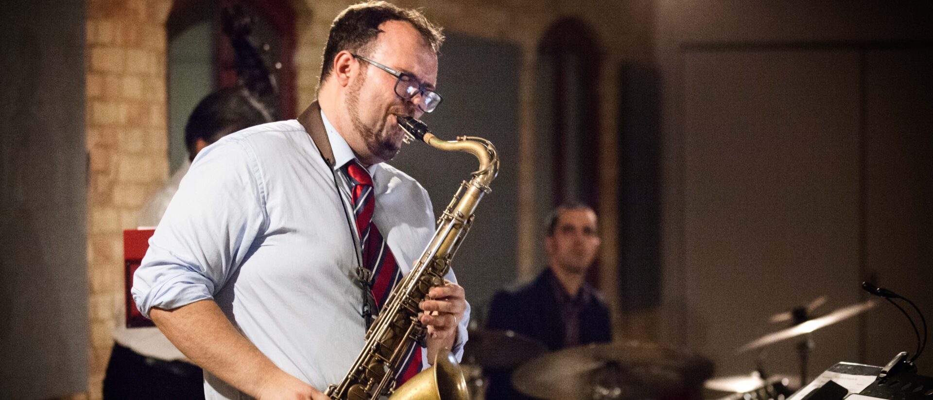 A man in a white shirt is playing the saxophone
