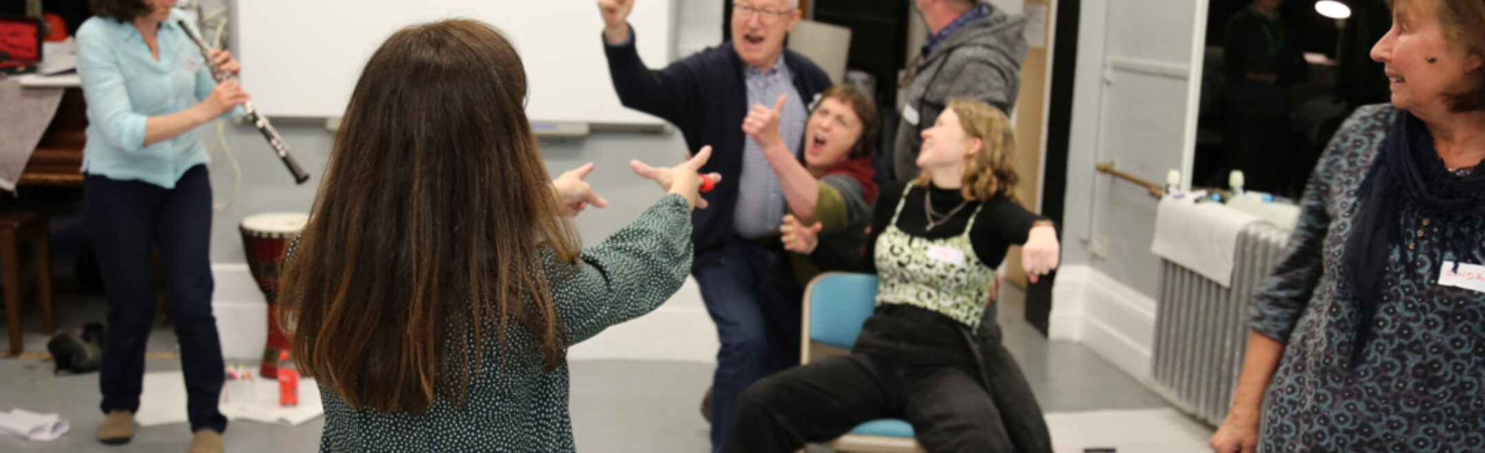 A 'freezeframe' image of participants of all ages making a dramatic tableau while someone plays the clarinet