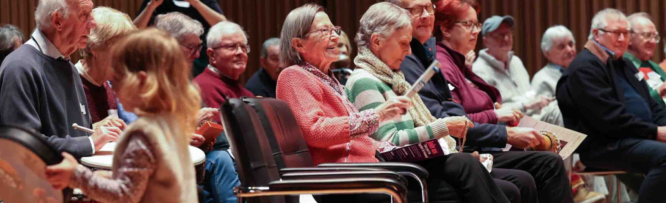 Together in Sound participants sitting next to each other smiling, and playing instruments