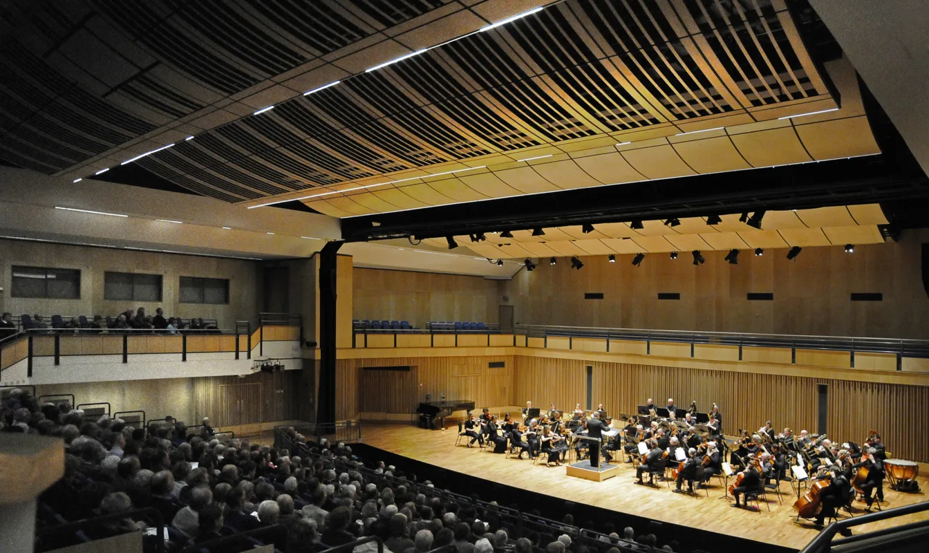 Side view of the wooden-clad auditorium with the audience sat in tiers in front of a performance from school musicians